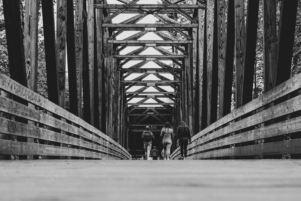 grayscale photography of people walking on bridge