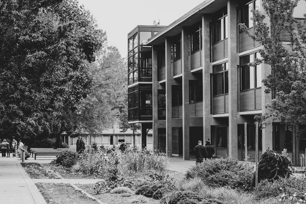 grayscale photography of few people near building