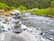Close-up of smooth river stones stacked carefully, surrounded by lush green moss.