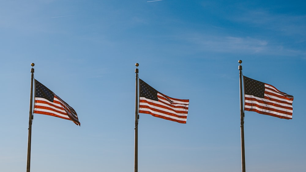 three USA flags hanging on pole