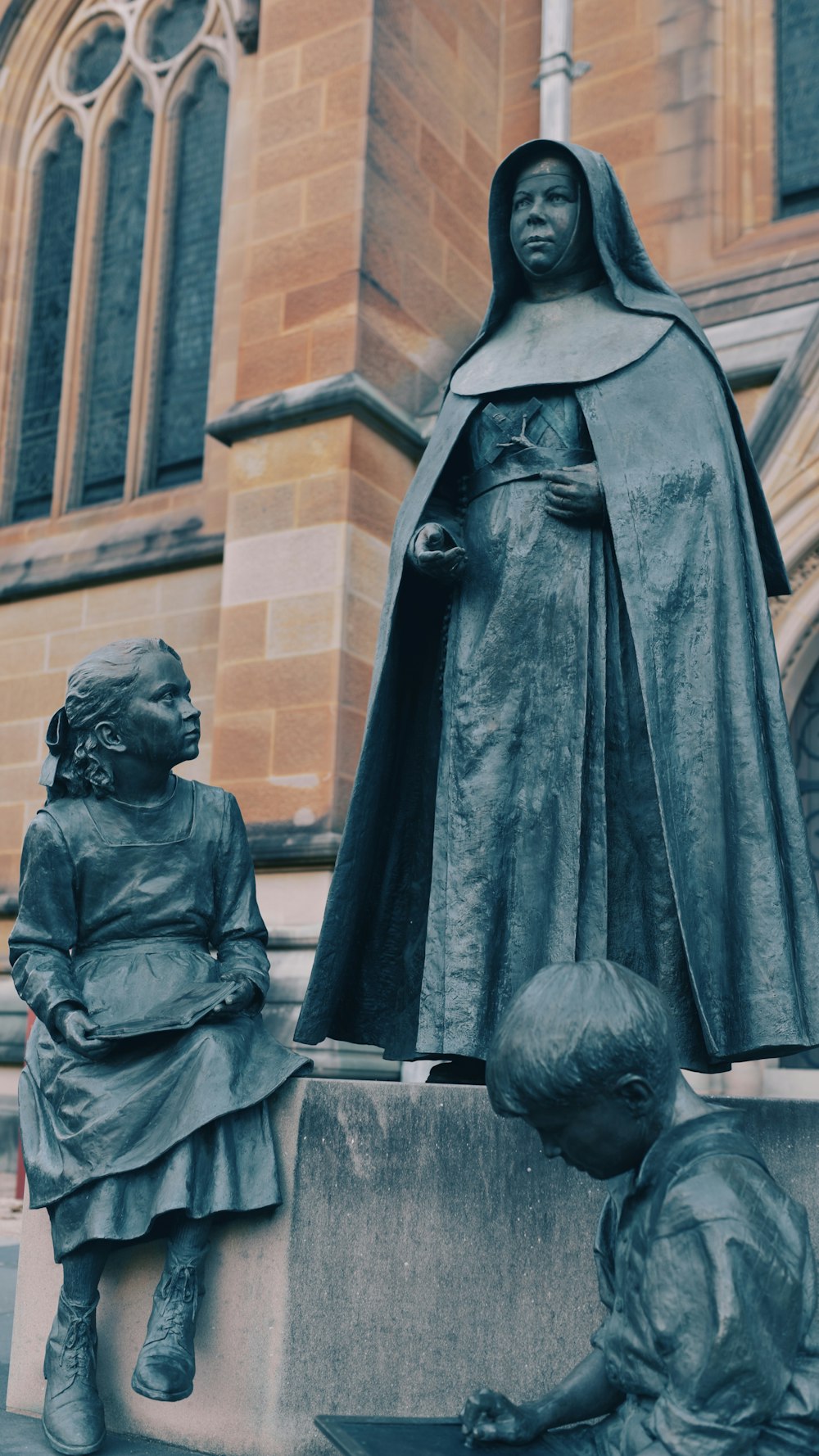 uma estátua de uma freira e duas crianças em frente a uma igreja