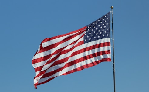 An American flag waving proudly against a clear blue sky, symbolizing patriotism and opportunity.