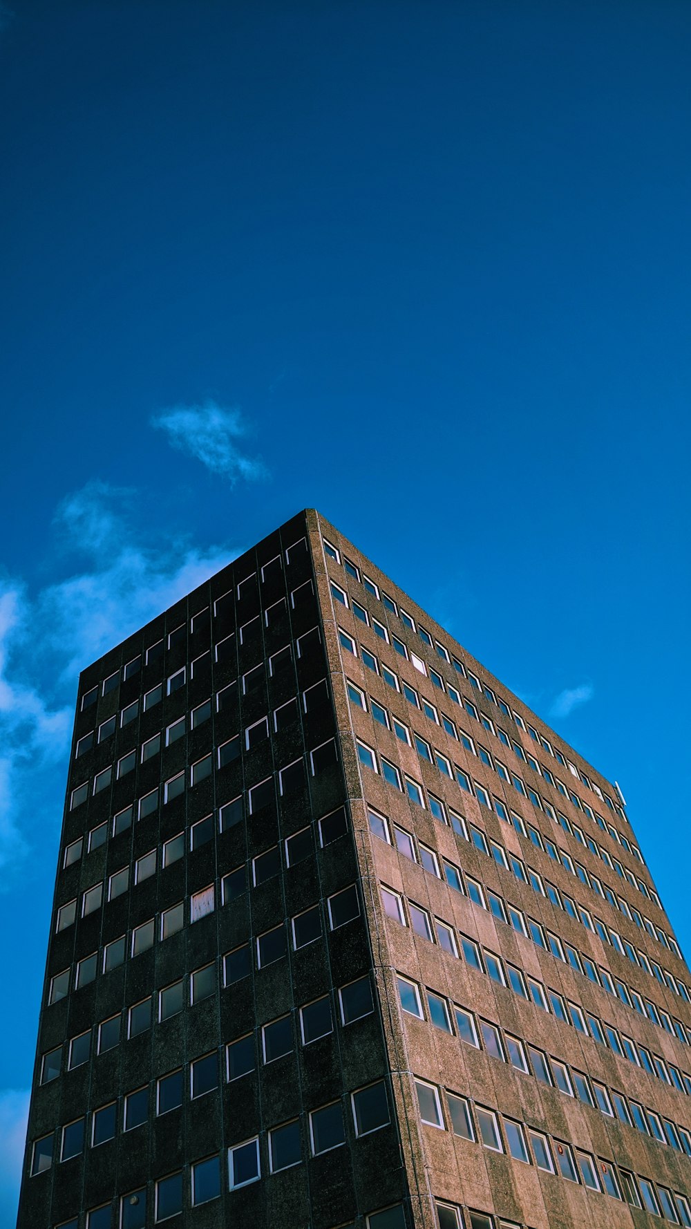 low-angle photography of brown concrete high-rise building under a calm blue sky during daytime