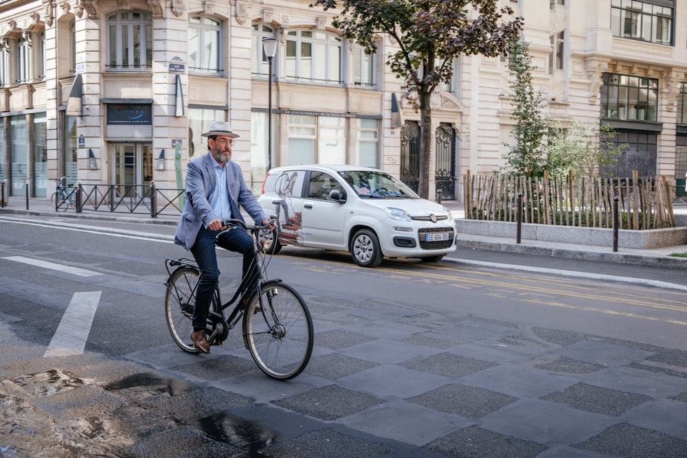 Hombre montando una bicicleta negra cerca de un hatchback blanco de 5 puertas