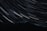 A dark mountainous landscape is illuminated by the long-exposure capture of numerous star trails, creating arcs of light across the night sky.