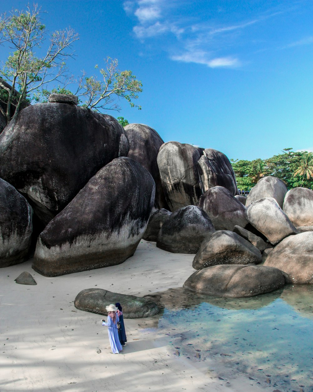 two person standing beside rock formation during daytime