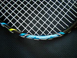 Close-up of a tennis racket being expertly strung with vibrant strings.