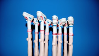 A row of stylized, cartoonish legs made from a soft material, possibly clay or plasticine, wearing white shoes with red and blue details. The background is a solid bright blue color.