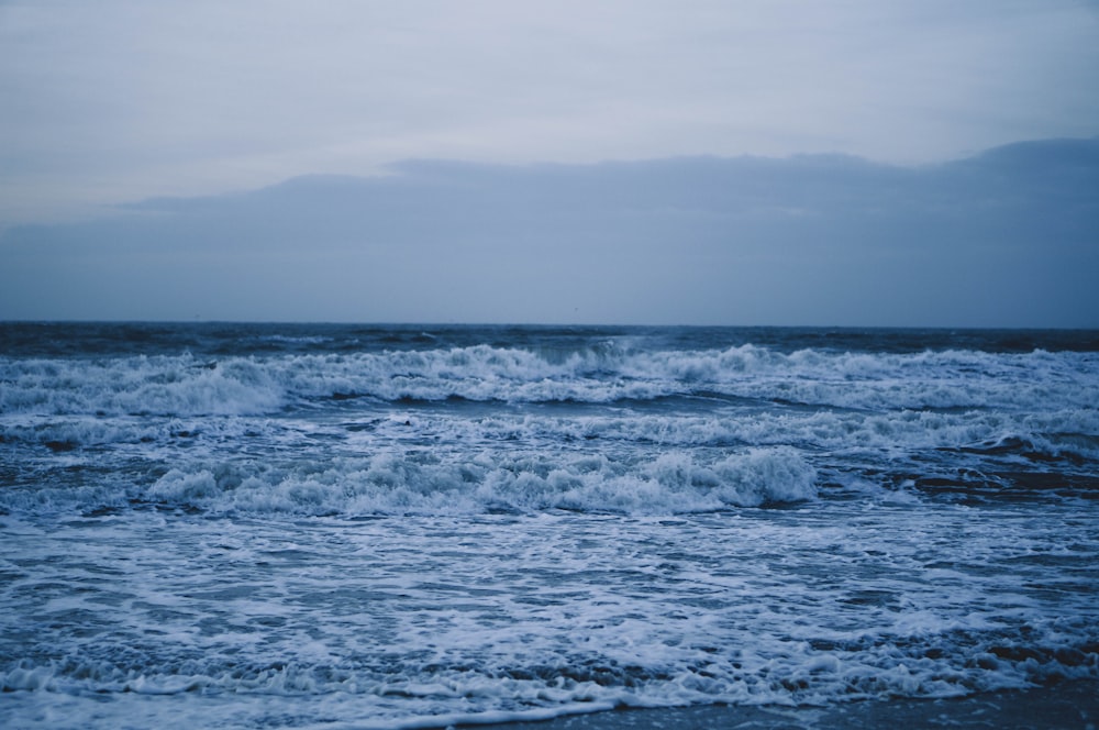 body of water under white sky at daytime