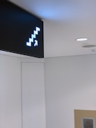 A well-lit directional sign guiding customers inside a busy office.