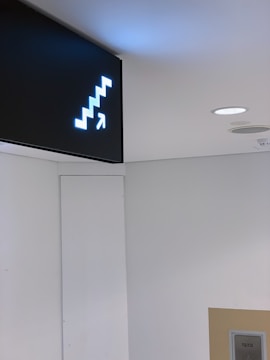 A well-lit directional sign guiding customers inside a busy office.