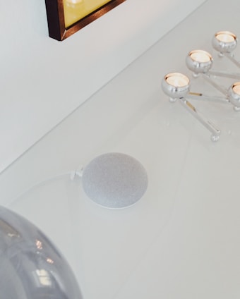 A smart home device on a minimalist shelf surrounded by cozy home decor.