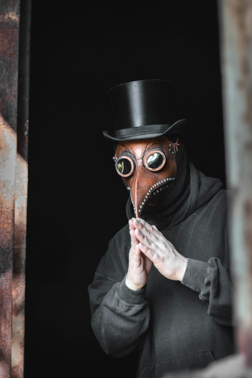 person wearing top hat and animal mask touching their own fingertips