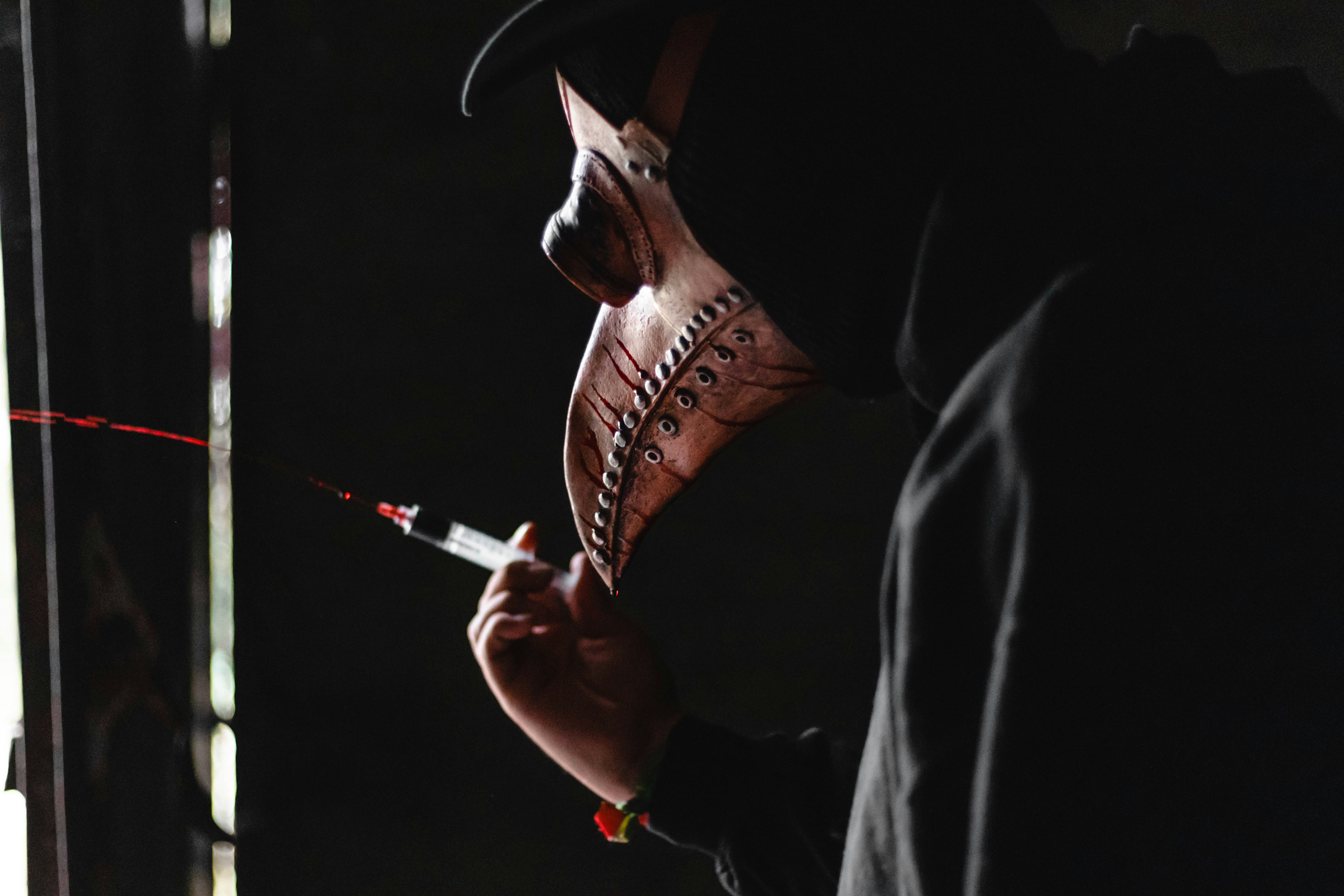 person pressing a syringe with red liquid