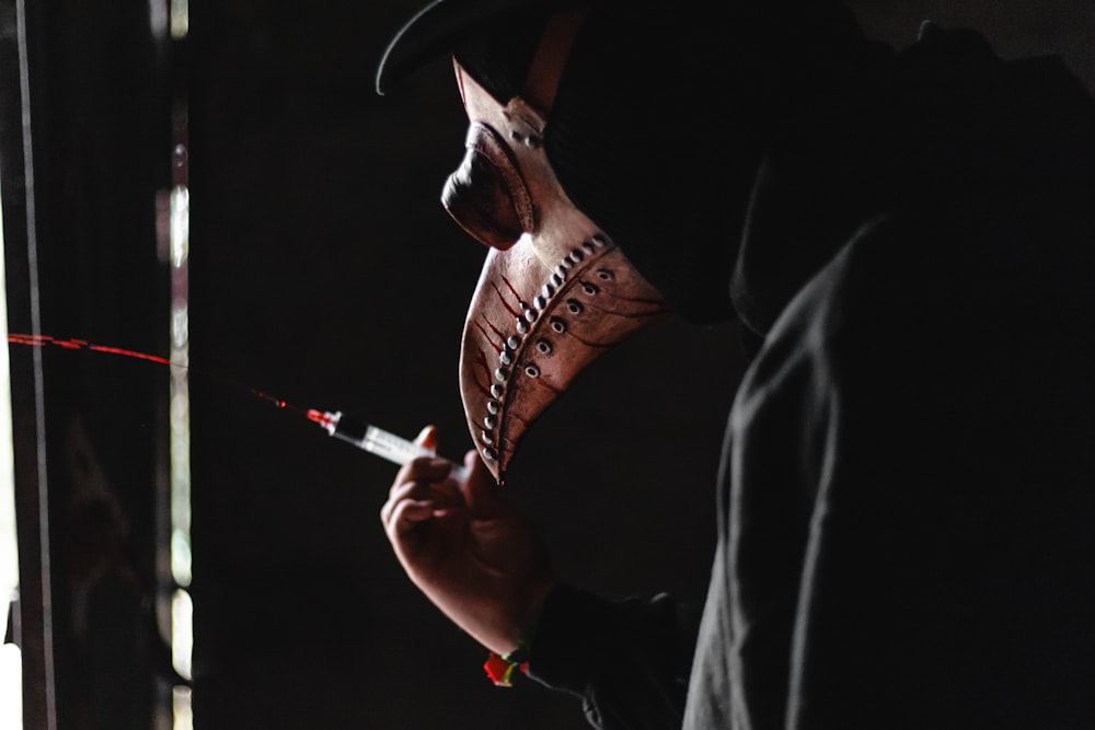 person pressing a syringe with red liquid