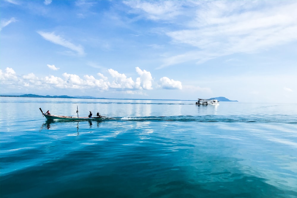 people riding boats floating at the ocean during day