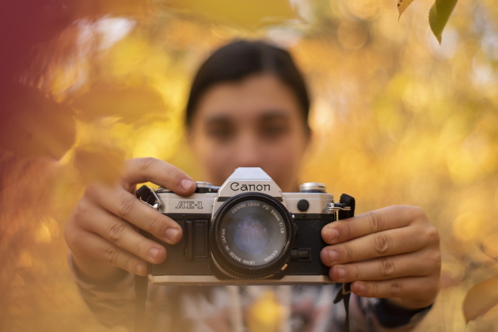 woman holding gray and black Canon camera