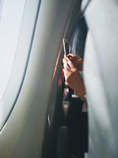 A smiling traveler booking flights on a smartphone with a bright, clean interface visible.