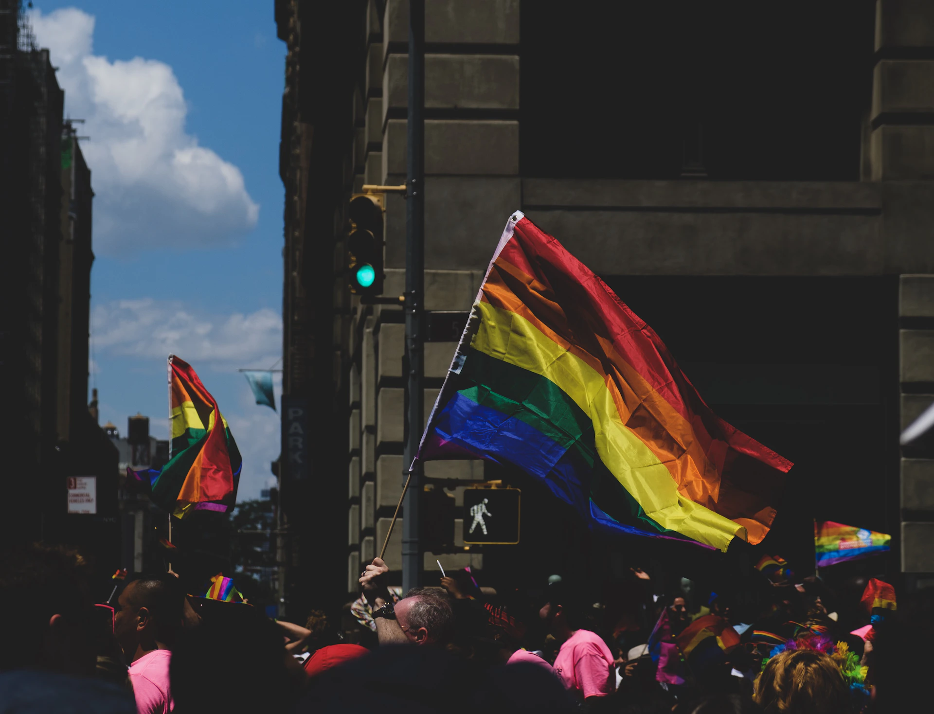 community of LGBT rallying near street under white and blue sky during daytime