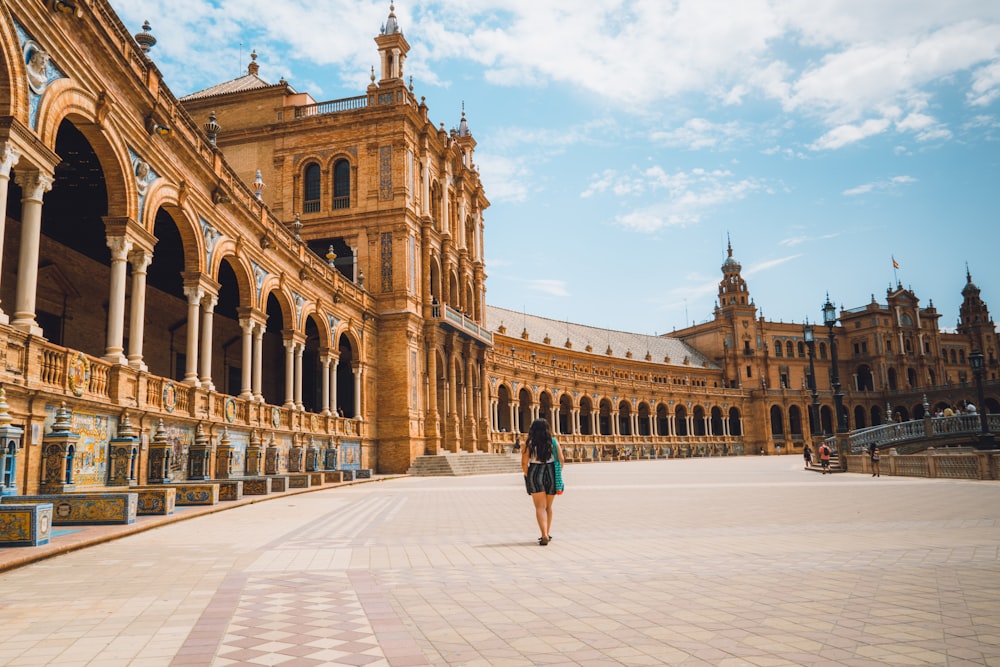 woman walking near Plaza de España in Mardid under blue and white sky during daytime