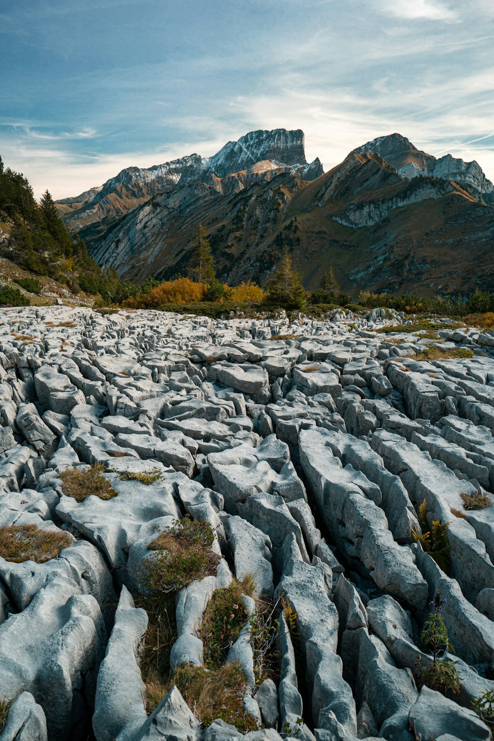Formations rocheuses grises regardant la montagne sous le ciel bleu et blanc pendant la journée