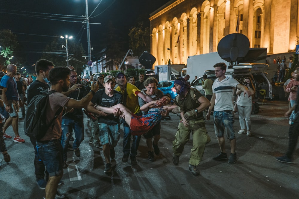 people carrying man near building