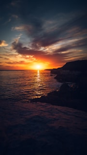 Sunset view at Uluwatu Temple with vibrant orange sky over the ocean cliffs.