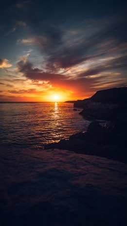 Sunset view at Uluwatu Temple with vibrant orange sky over the ocean cliffs.