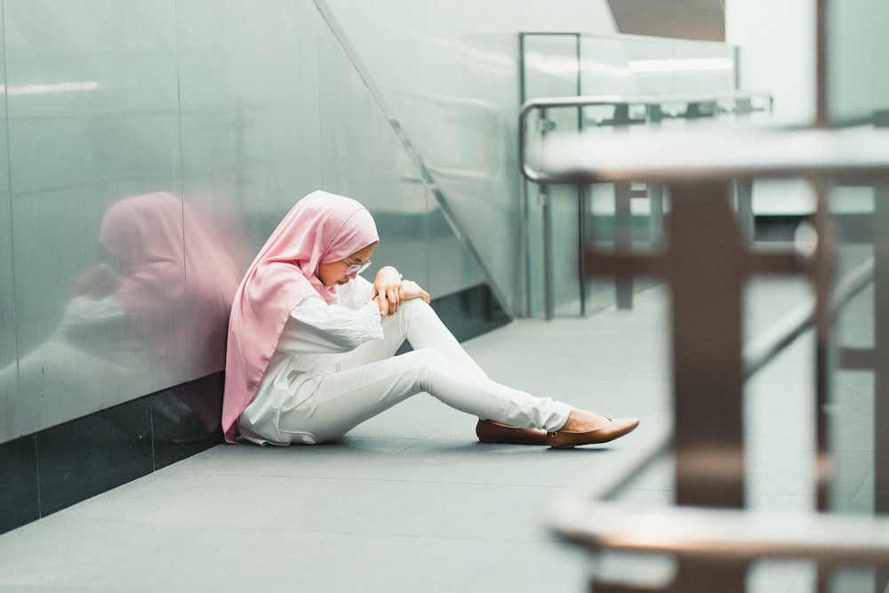 woman sitting on floor while leaning on glass wall