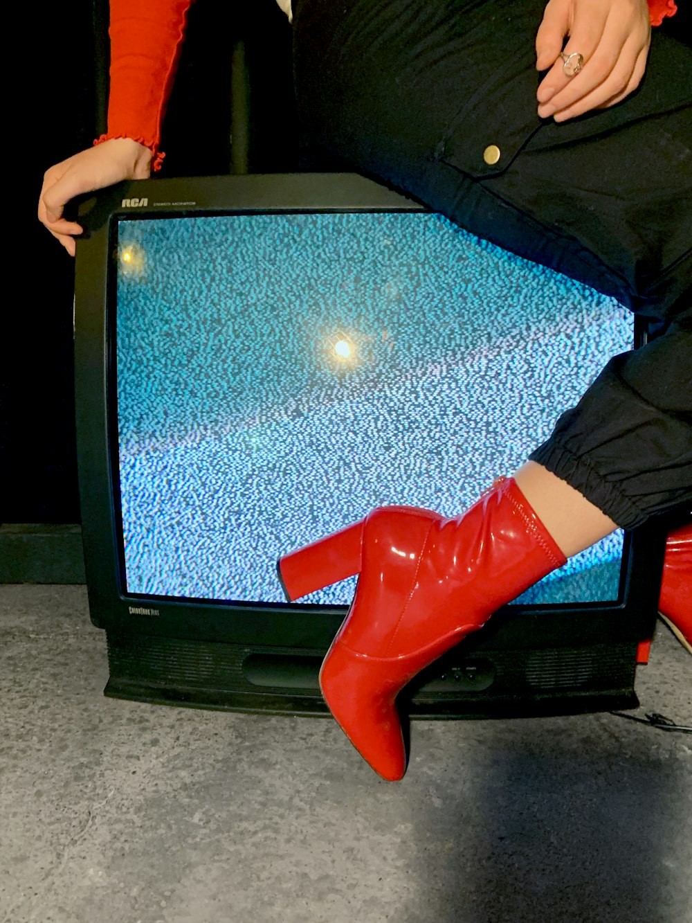 mujer sentada en un televisor CRT negro