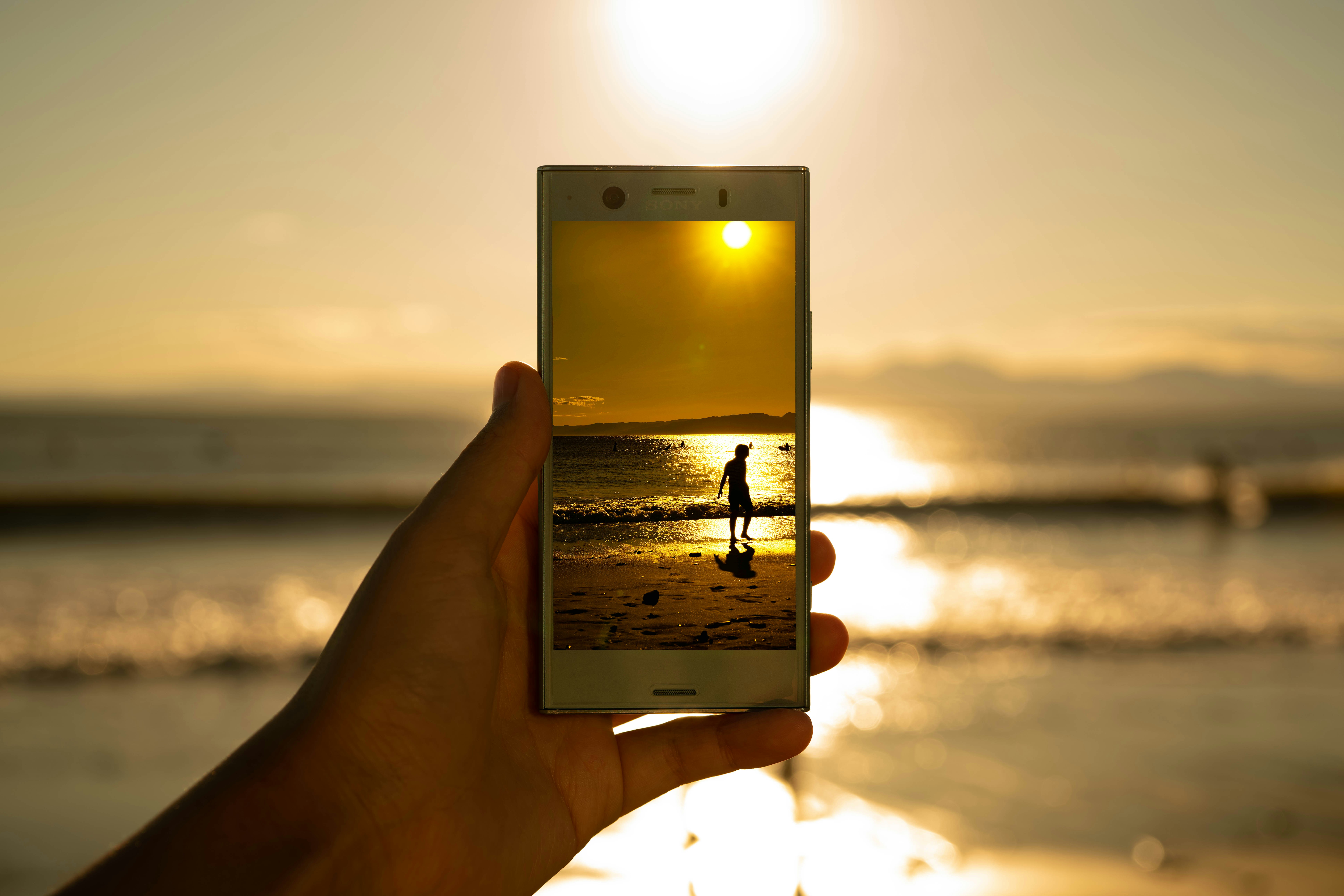 person holding phone showing person on seashore
