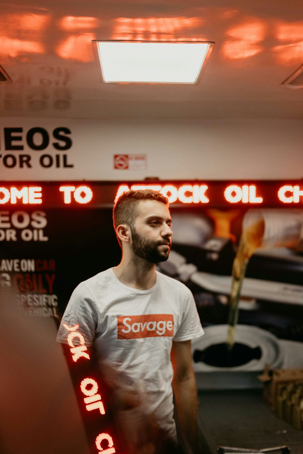 man in white shirt with Savage print inside a lighted room