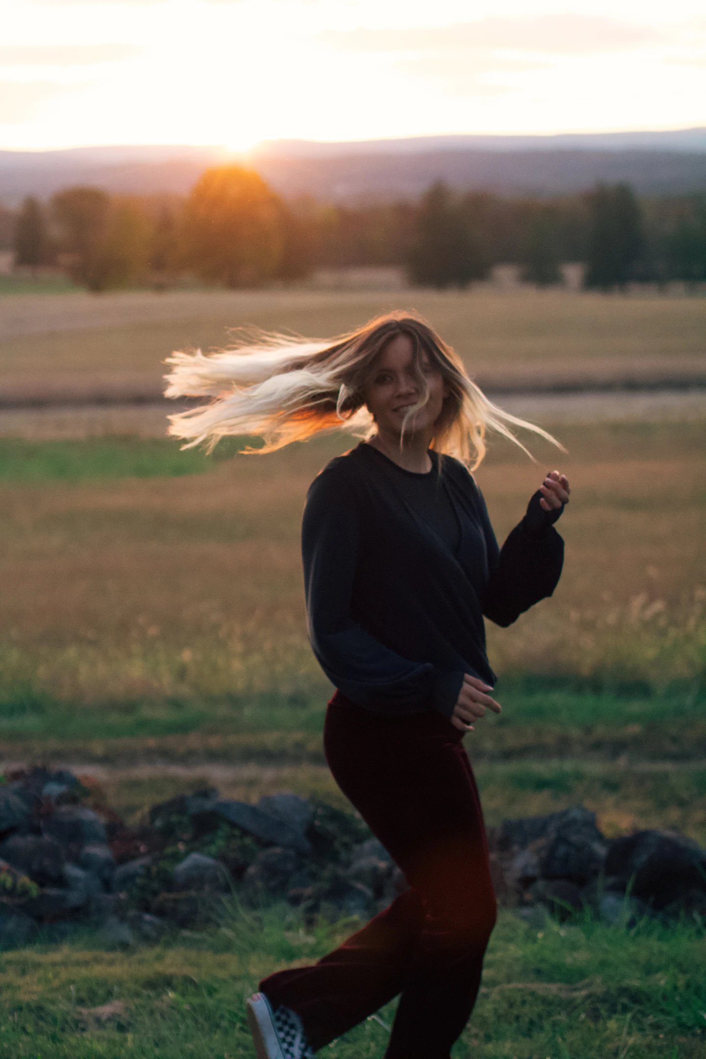A woman spinning in a field at dusk