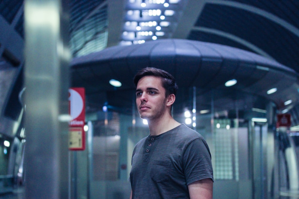 man in black t-shirt standing beside gray metal wall