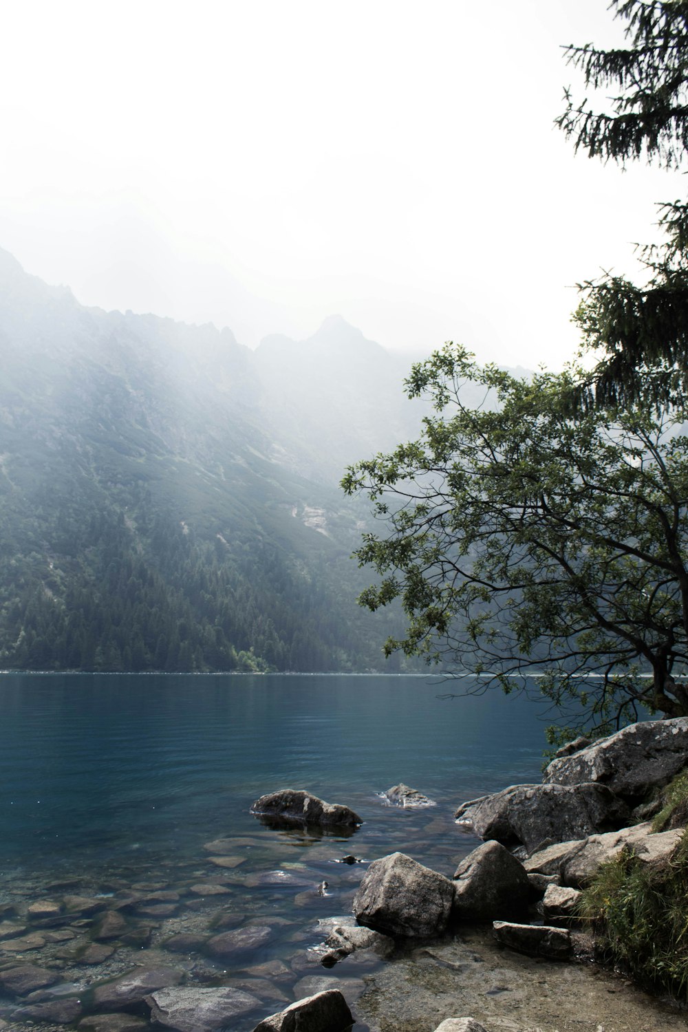 calm body of water by mountain