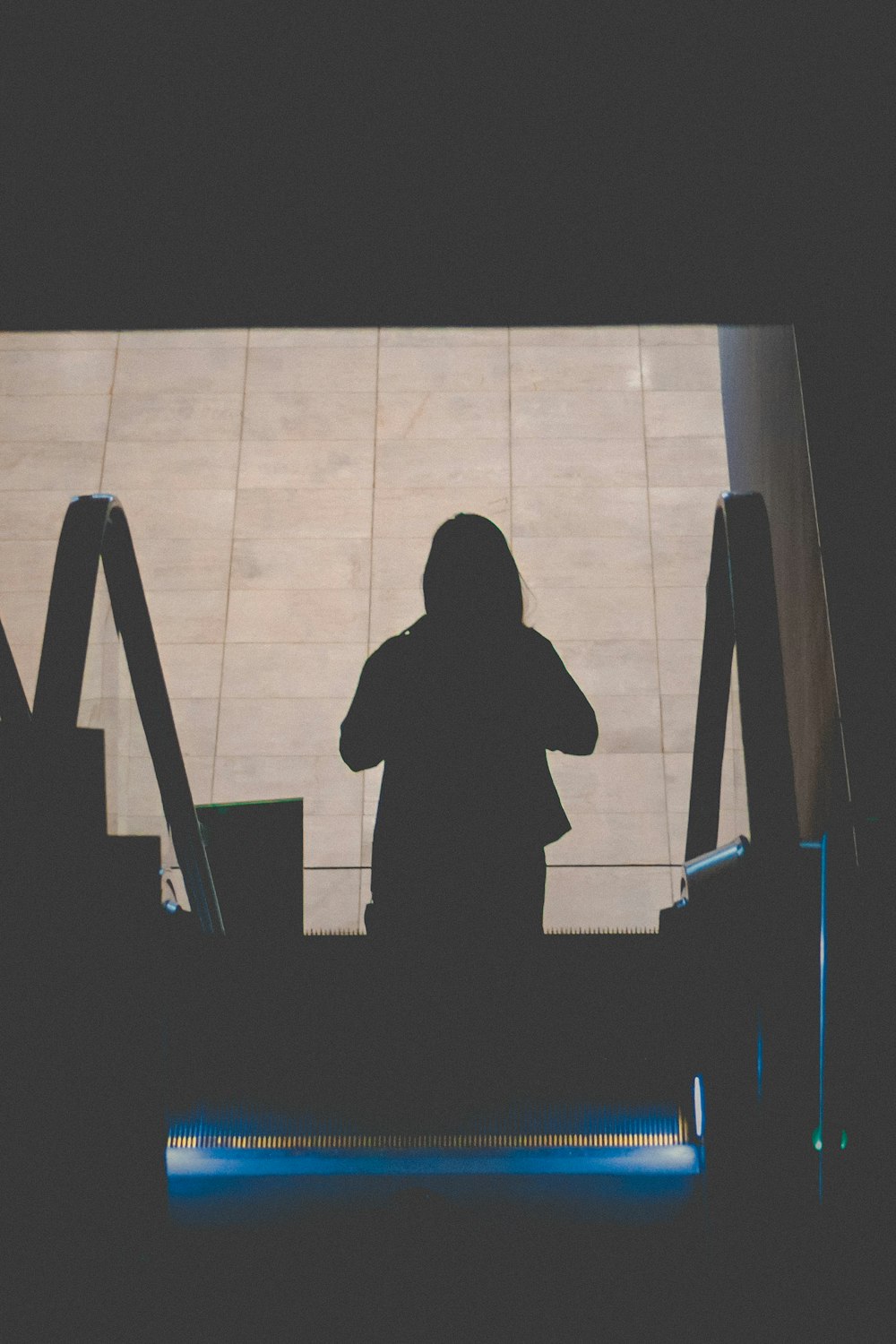 silhouette photography of person standing on escalator
