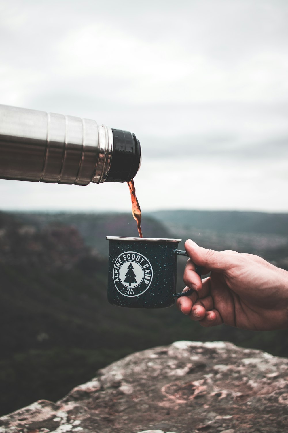 a person holding a coffee cup with a mountain in the background