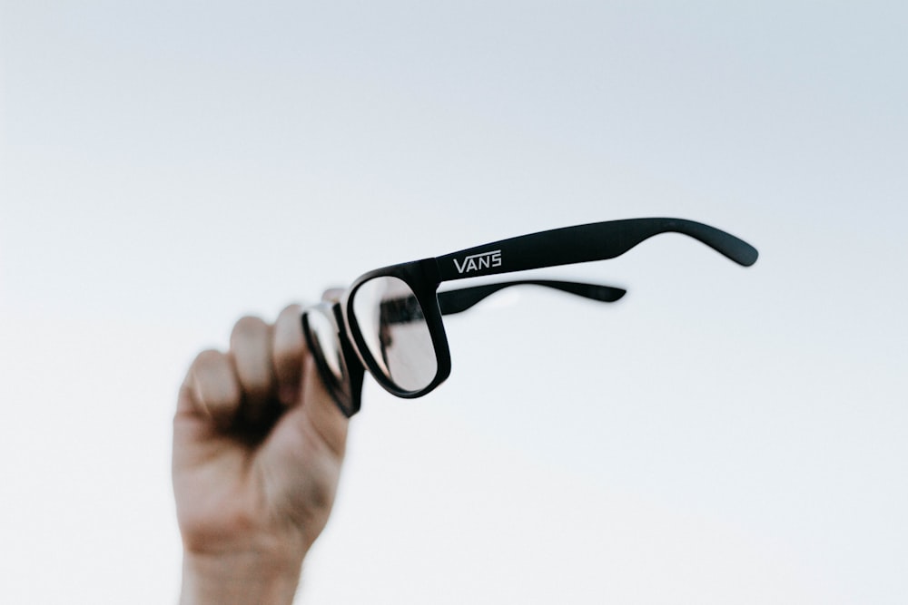 a hand holding up a pair of glasses