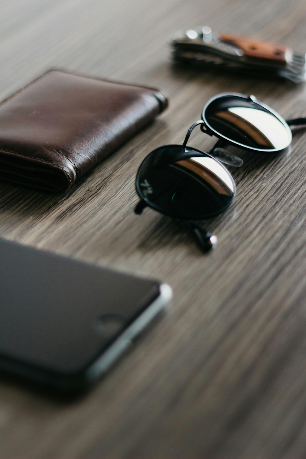 Gafas de sol Ray-Ban negras junto a cartera de cuero marrón