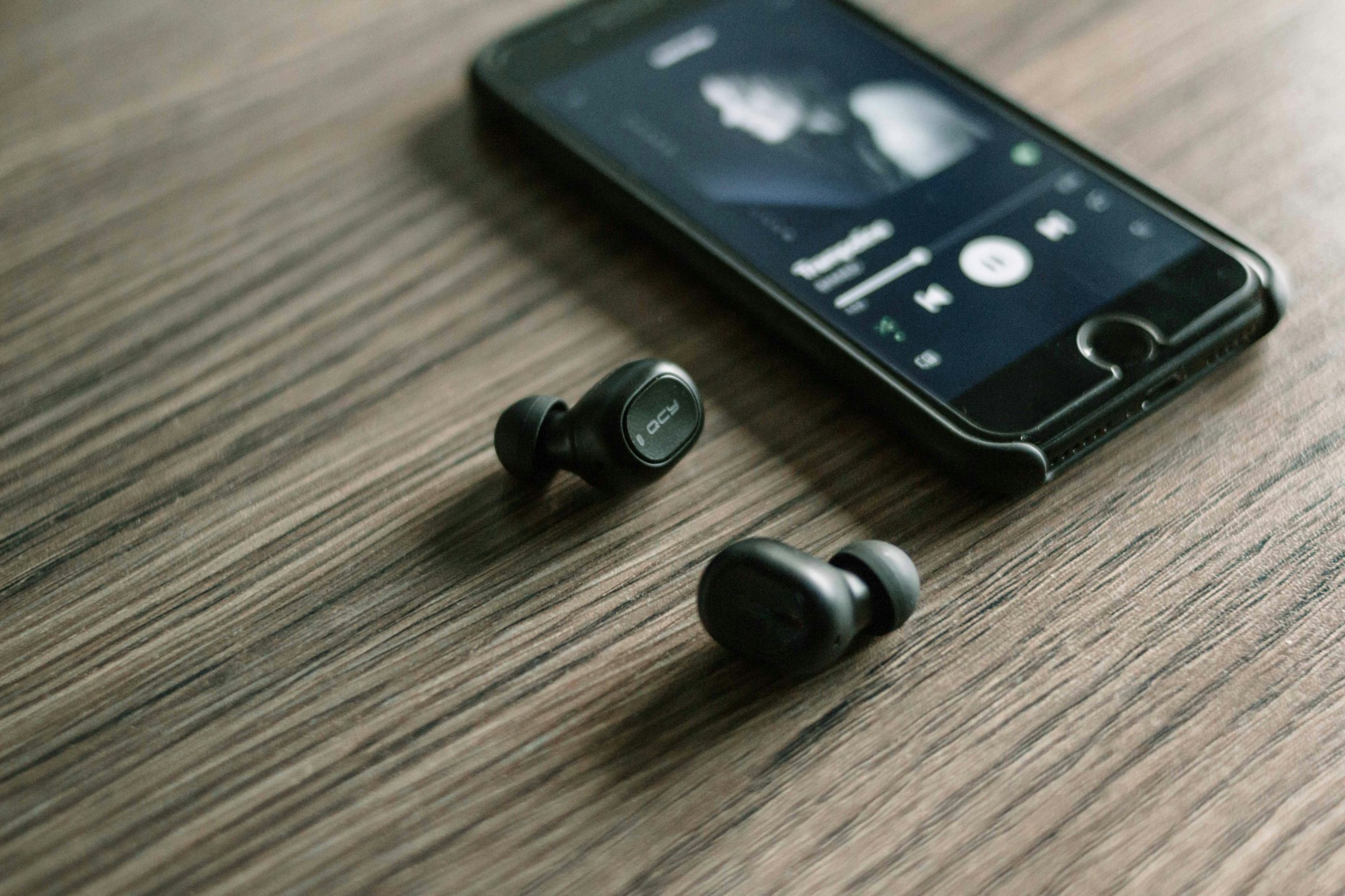 wireless earphones sitting on table with cell phone