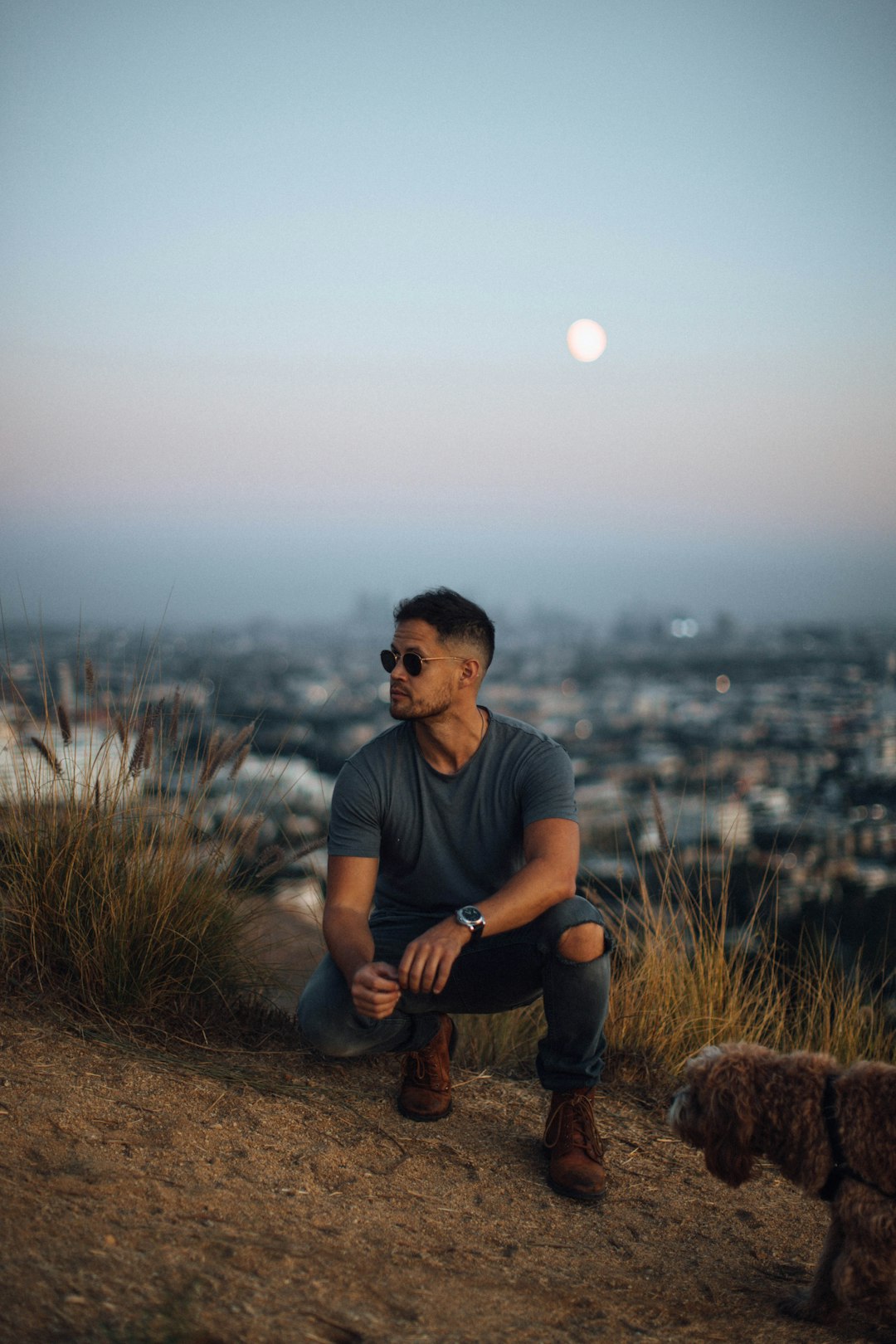 man wearing grey t-shirt sitting beside grass