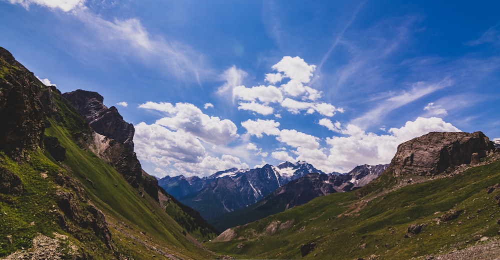 green and gray mountain under white and blue cloudy sky