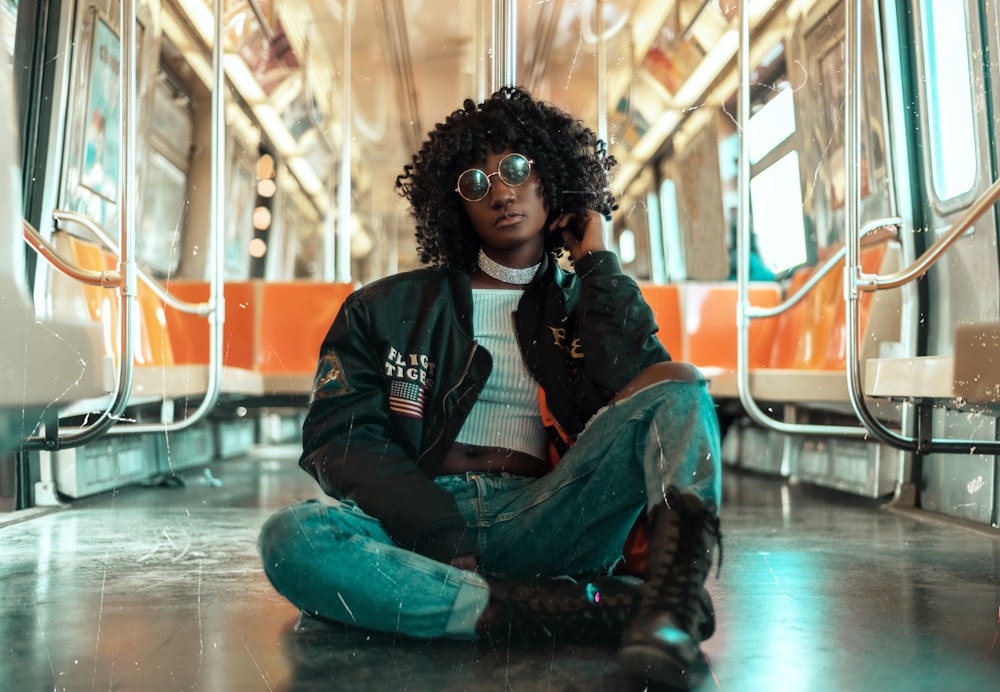 woman wearing black jacket and denim jeans sitting inside train