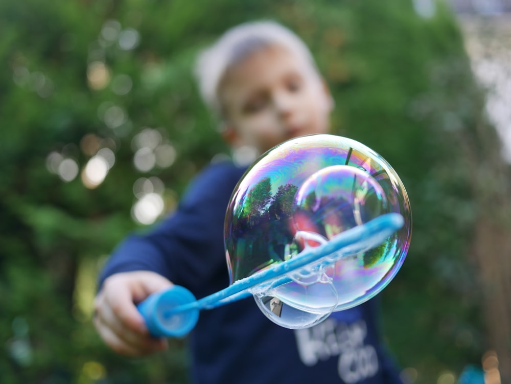 boy playing bubbles near tree