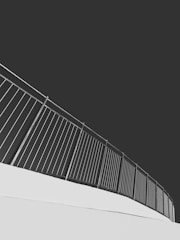 An upward-sloping metal railing set against a stark contrast of light and dark tones, creating a modern and minimalist aesthetic.
