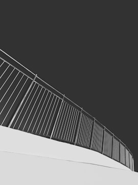 An upward-sloping metal railing set against a stark contrast of light and dark tones, creating a modern and minimalist aesthetic.