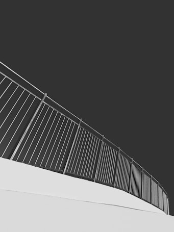An upward-sloping metal railing set against a stark contrast of light and dark tones, creating a modern and minimalist aesthetic.