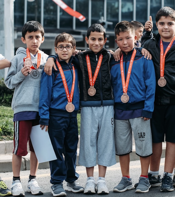 group of children wearing medal standing near wall