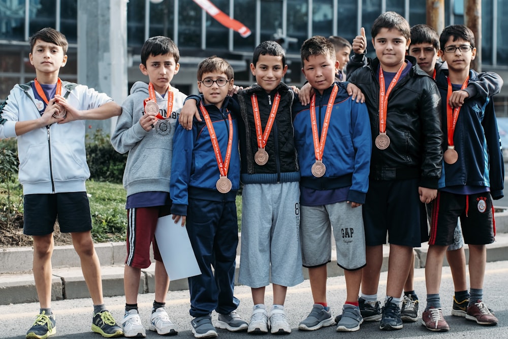 group of children wearing medal standing near wall