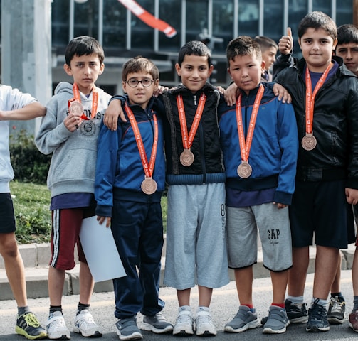 group of children wearing medal standing near wall